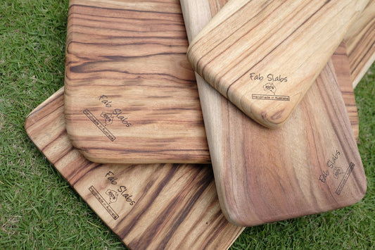 a pile of wooden cutting boards sitting on top of a green field