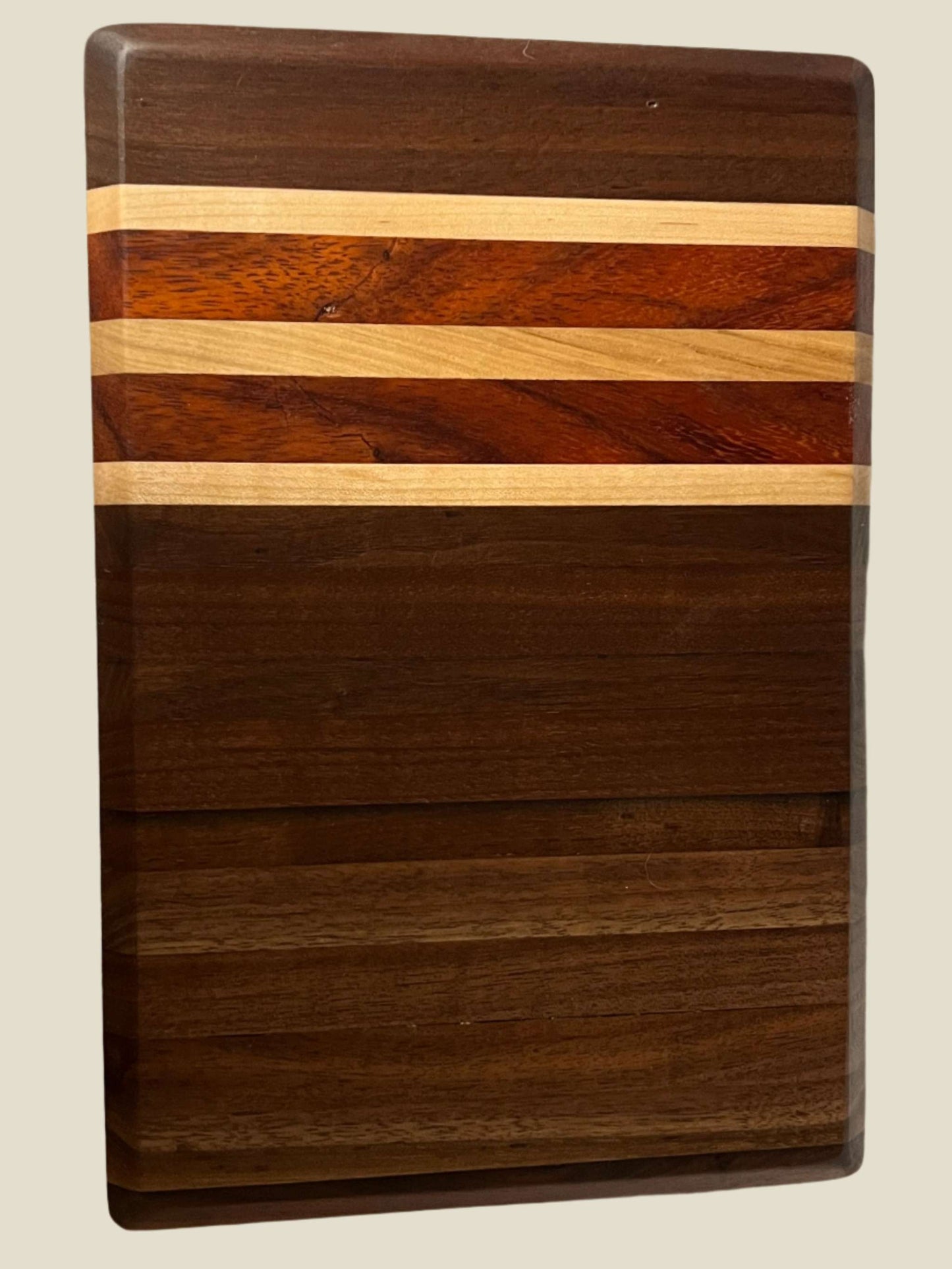 Handmade 8"x12" chopping board in Black Walnut, Maple, and Padauk showcasing craftsmanship and utility.