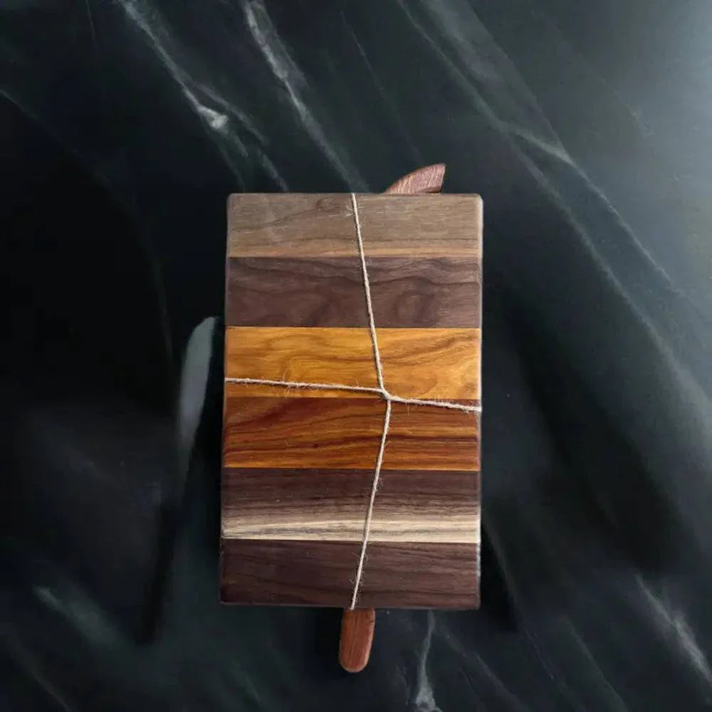 Handmade Black Walnut and Canarywood bread board with knife on dark surface, 12x7.5x3/4 inches.