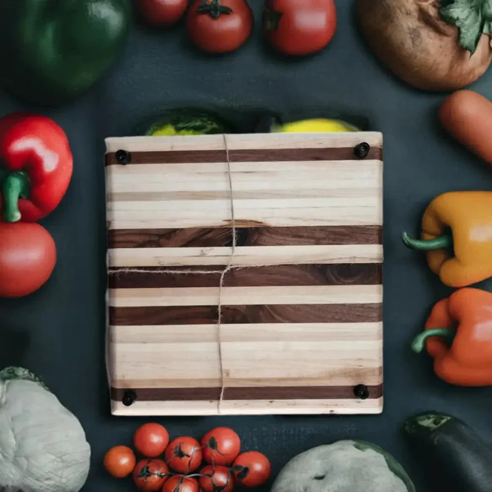 12x12x1.5 inch artisan butcher block with peg feet made of Hard Maple and Black Walnut, surrounded by fresh produce.