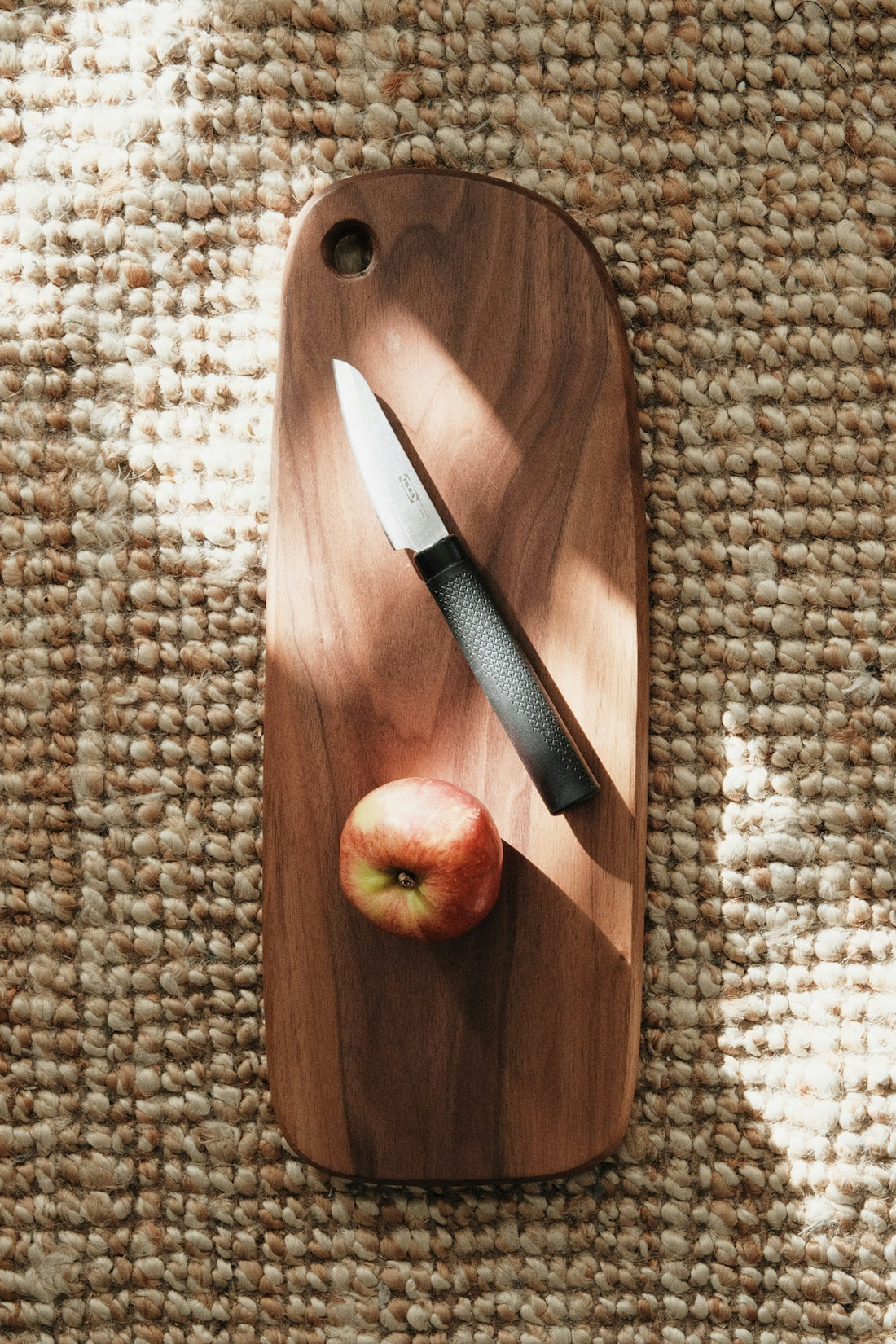 a cutting board with a knife and an apple on it