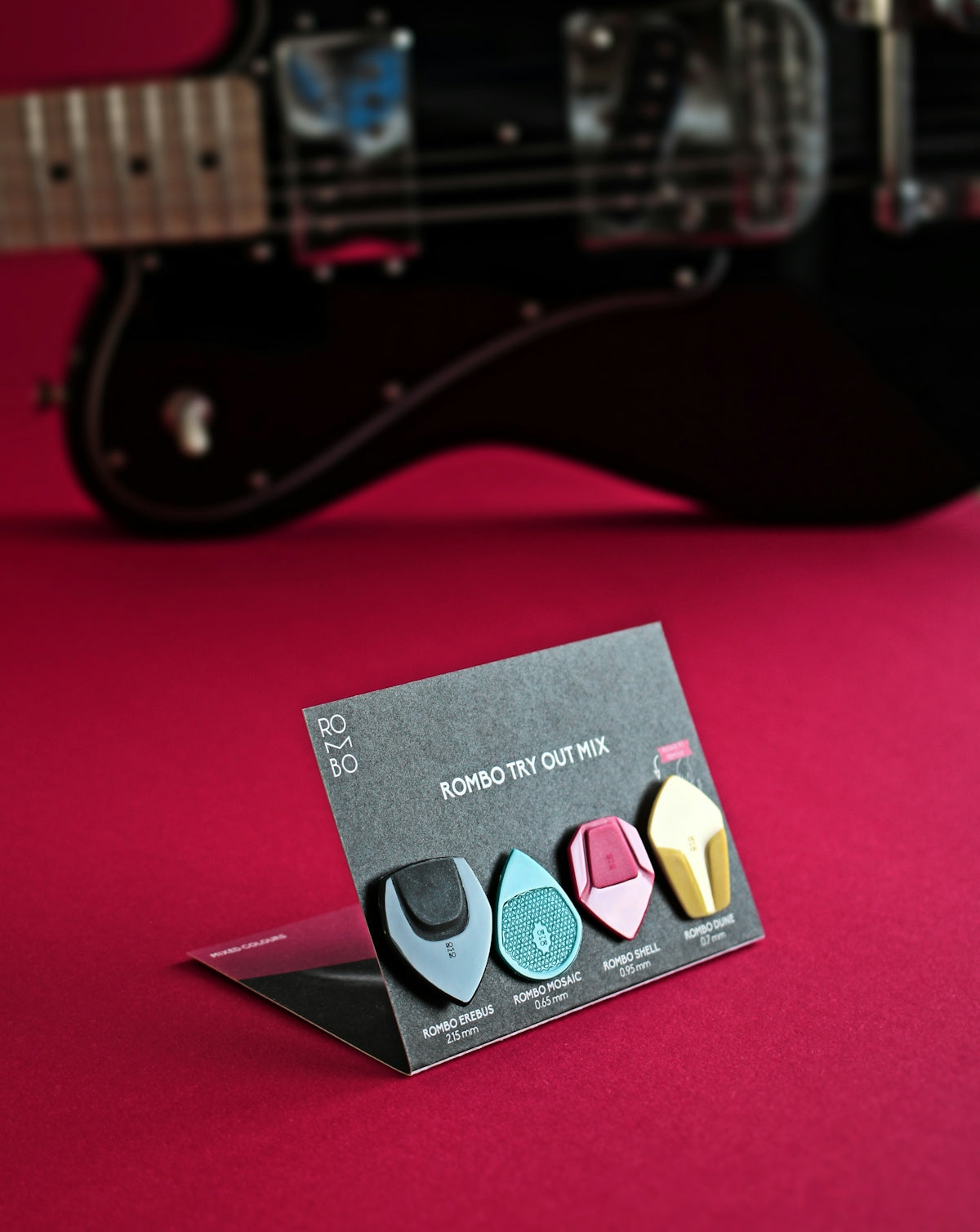 a set of three guitar picks sitting on top of a red surface