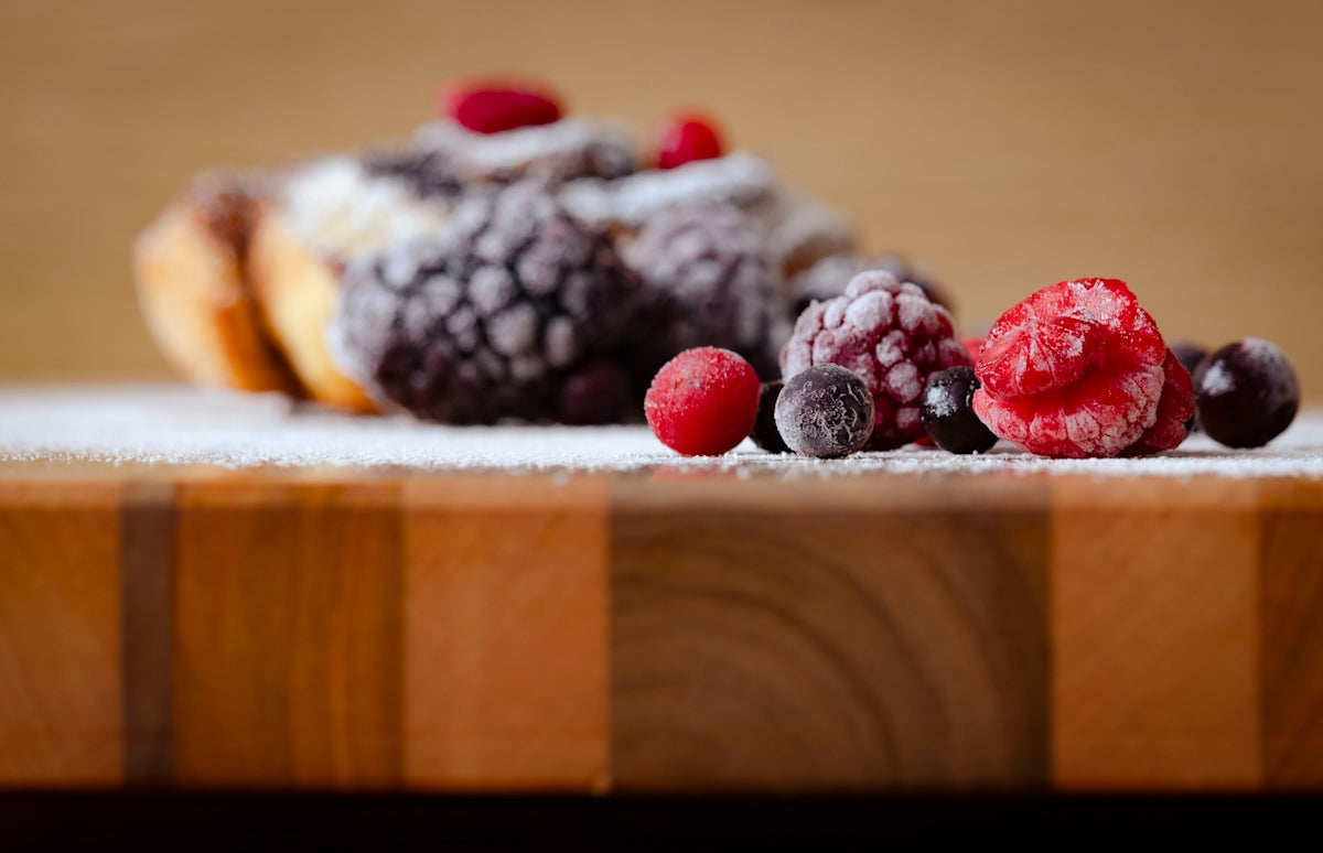 a wooden cutting board topped with berries and powdered sugar