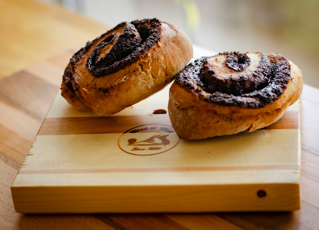 two cinnamon rolls sitting on top of a cutting board