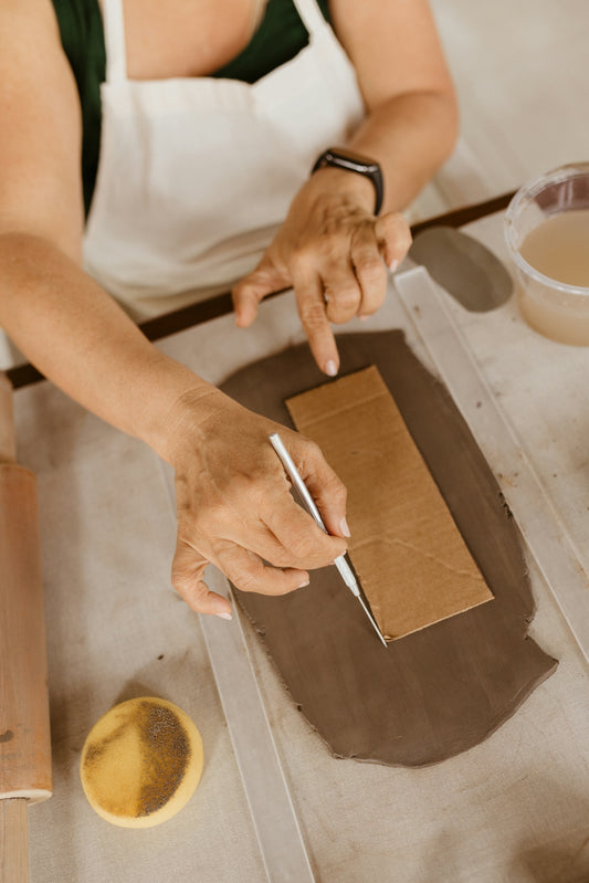 A woman in an apron is cutting a piece of cardboard