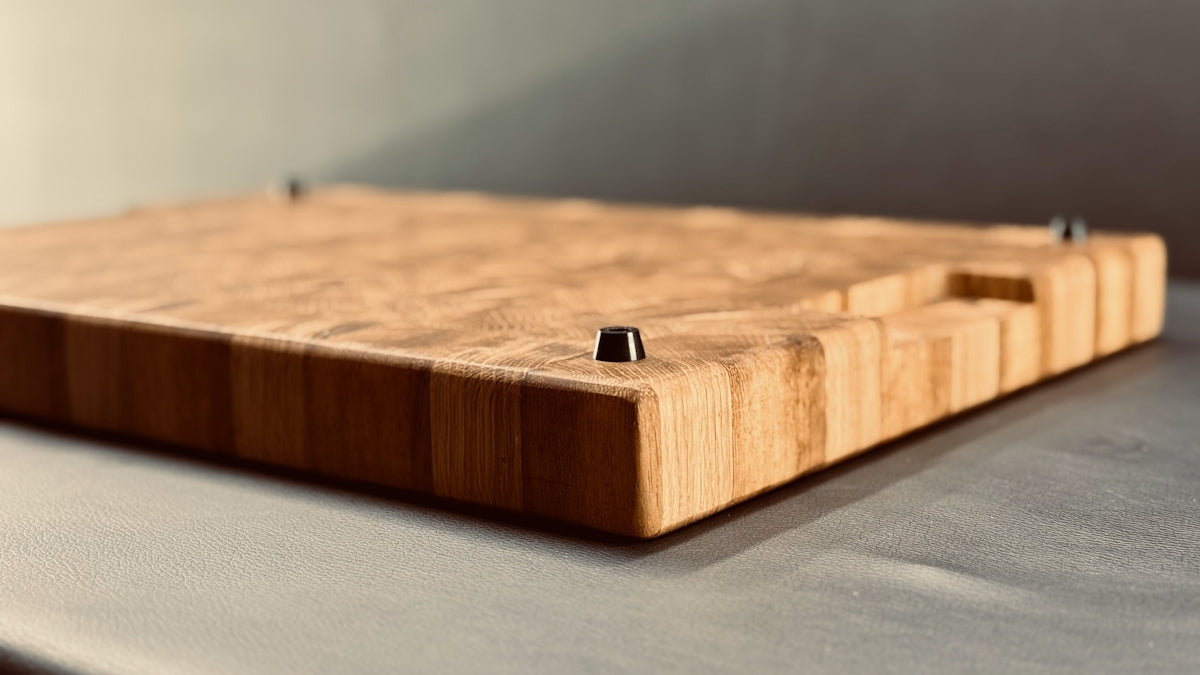A wooden cutting board is shown in a side angle.