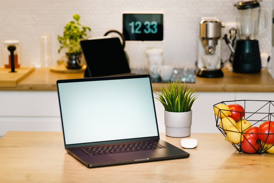 A laptop sits on a kitchen counter workspace.