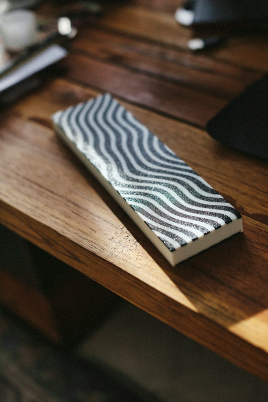 A rectangular block with wavy lines sits on wood.
