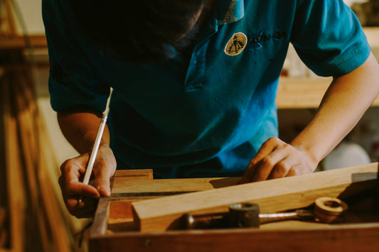 Person measuring wood with a pencil and ruler