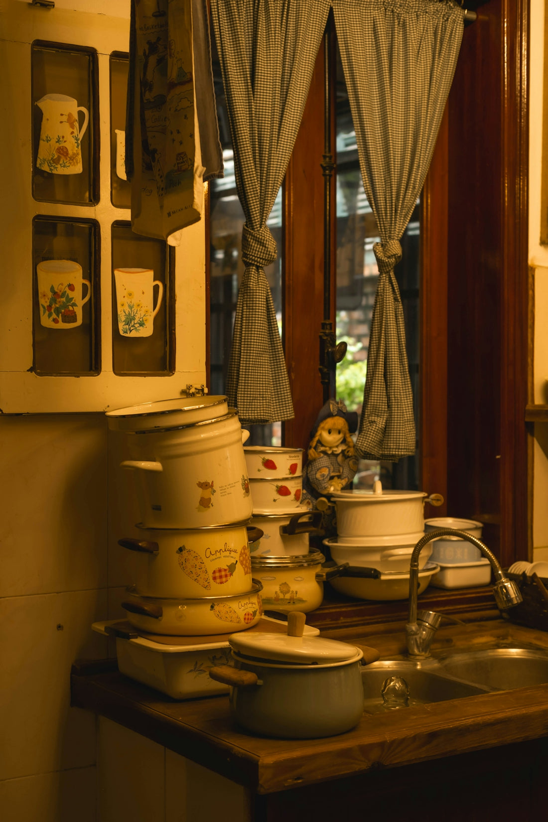 Stack of vintage pots and pans by a kitchen sink.