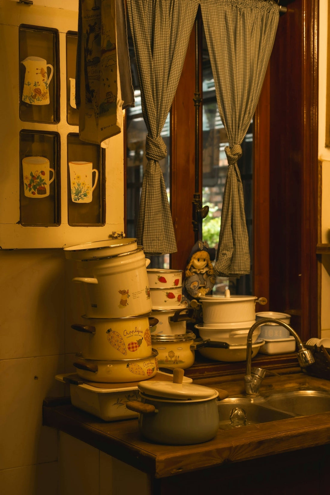 Stack of vintage pots and pans by a kitchen sink.