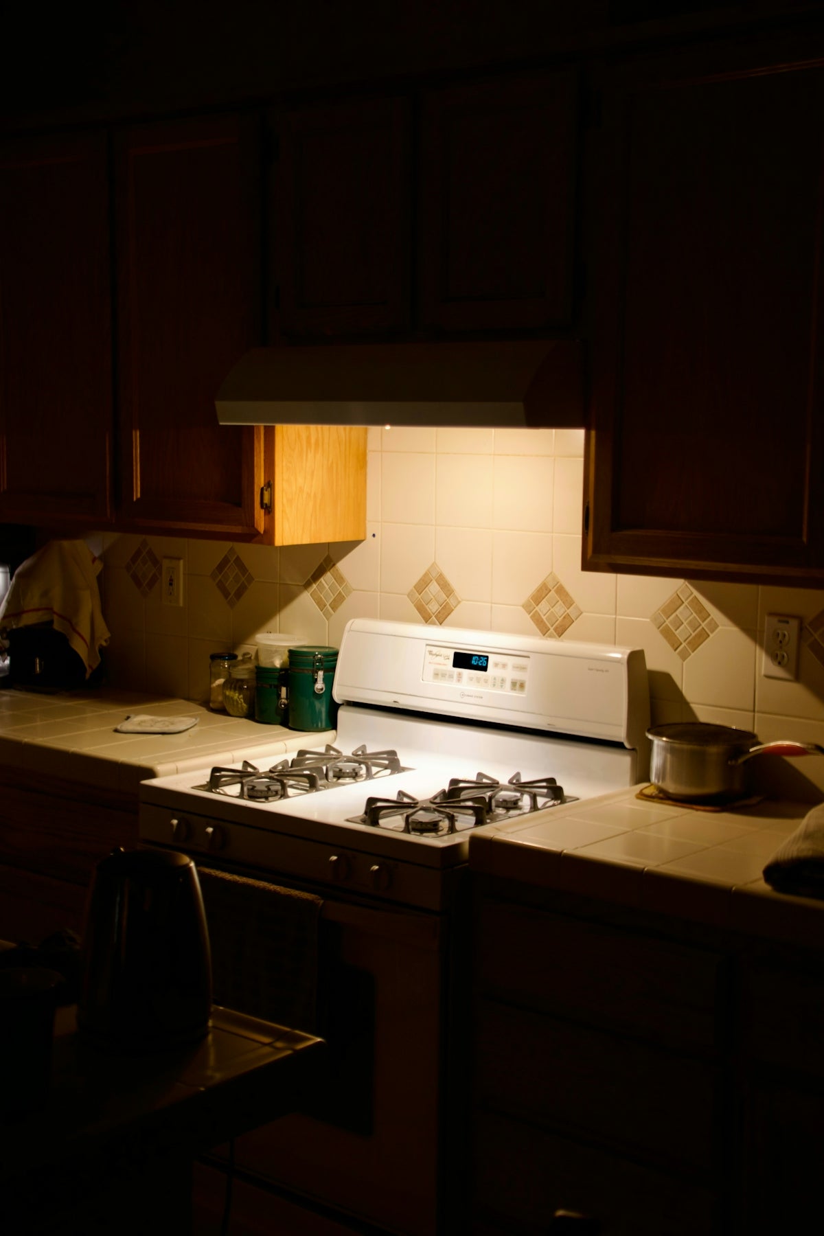 A white gas stove with cabinets above it.