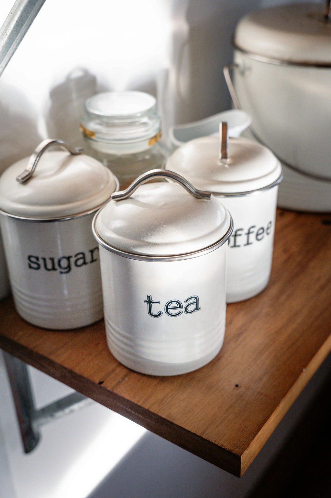 White kitchen canisters labeled tea, sugar, and coffee.