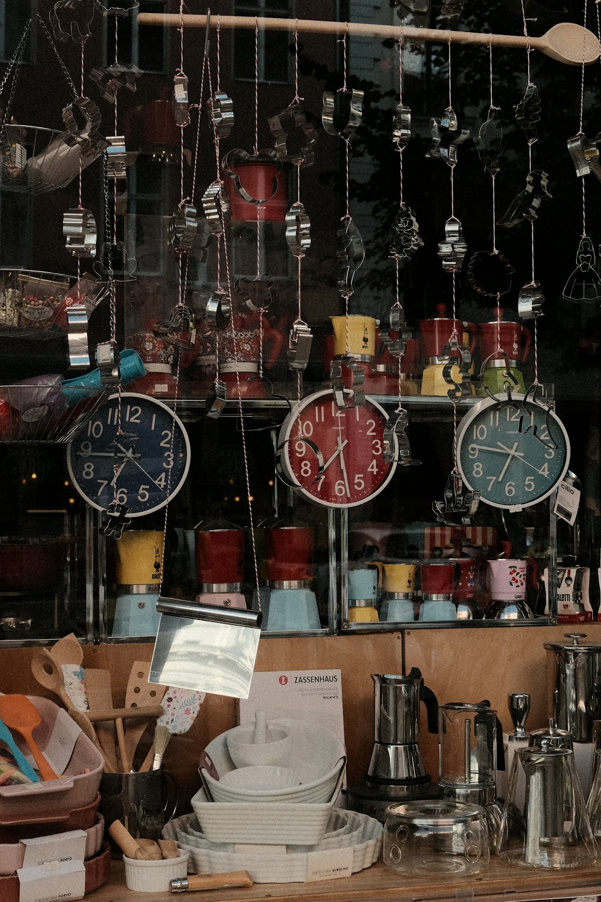 Shop display with colorful clocks, coffee makers, and kitchen utensils.