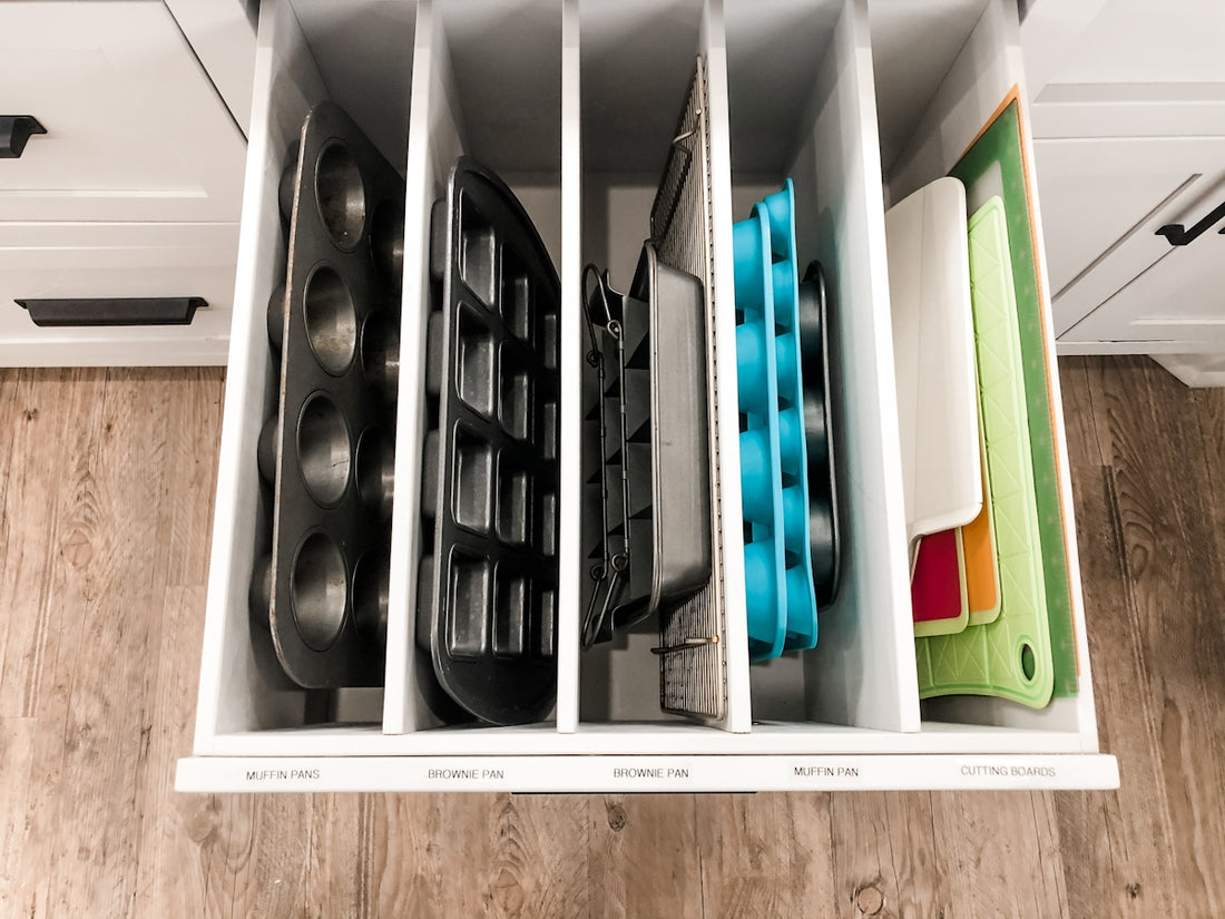 A kitchen drawer with vertical dividers organizing baking pans and colorful cutting boards.