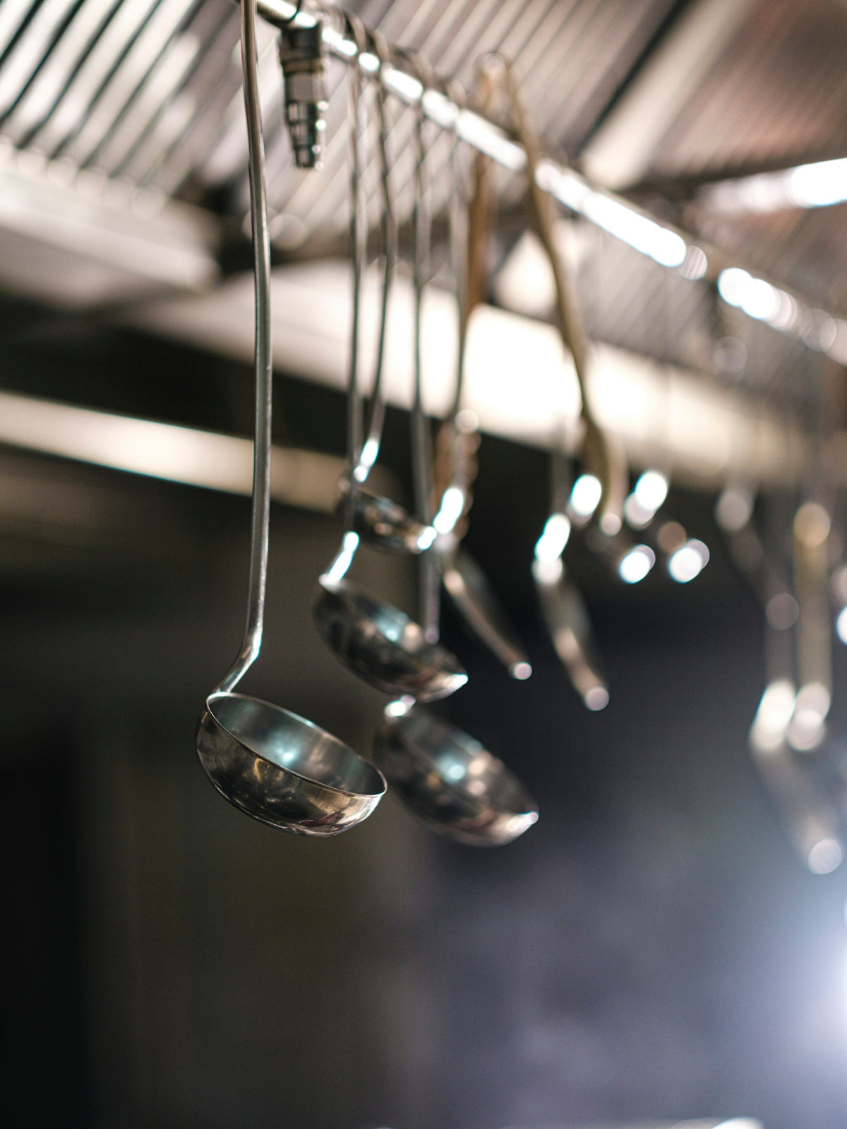 Metal ladles hanging from a rack in a professional kitchen