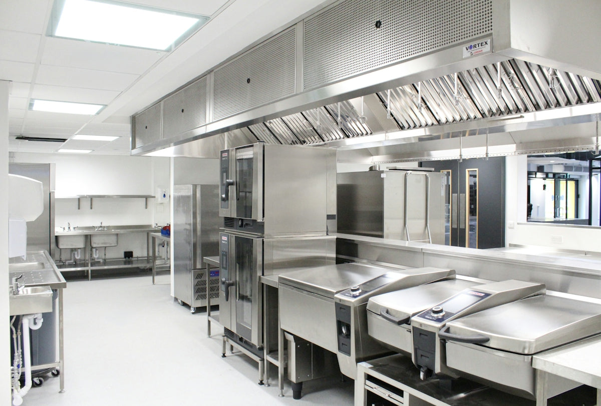 A commercial kitchen with stainless steel appliances and a large ventilation hood
