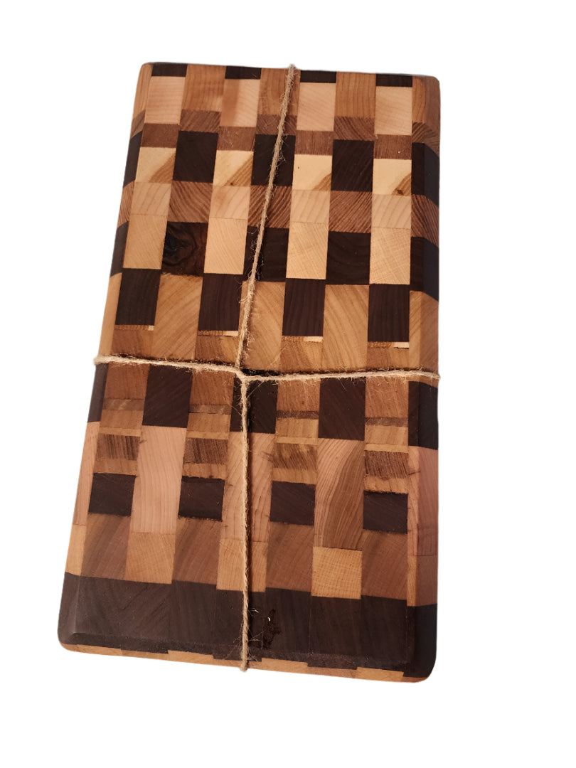 Handcrafted mini end grain chopping board made from black walnut, cherry, and maple wood with intricate pattern, tied with twine.